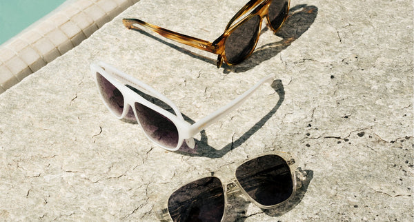 Three pairs of sunglasses by 8JS positioned by the side of the swimming pool