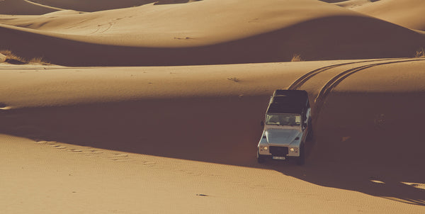 A Land Rover Defender driving over sand dunes