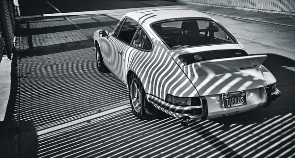 a black and white shot of a Porsche 911 with shadow stripes