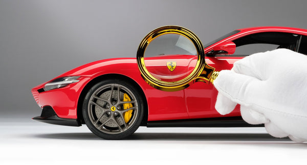 A studio image of a scale model of a Ferrari Roma by Amalgam Collection inspected with a magnifying glass