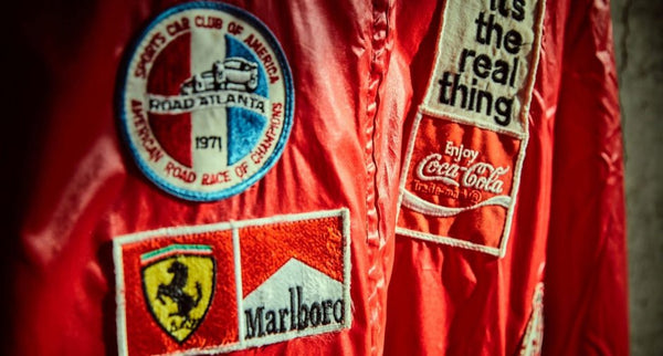 A red jacket with badges with brands including Ferrari, Marlboro and Coca Cola