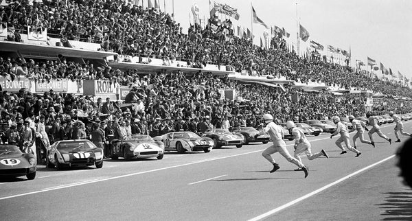 A period image of racing drivers running to get into their cars at Le Mans